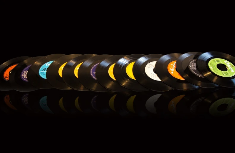 a row of vinyl records on a reflective surface, by Doug Ohlson, hero shot, acrylic, bright on black, packshot