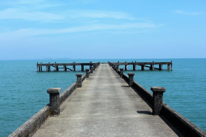 a long pier stretches out into the ocean, a picture, by Tadashige Ono, shutterstock, concrete pillars, in style of thawan duchanee, sunny day with clear sky, stock photo