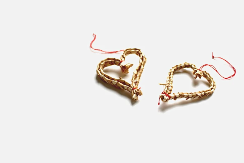 a couple of heart shaped ornaments sitting on top of a table, by Emma Andijewska, tumblr, folk art, weaving, broken gold shackles, side view intricate details, straw