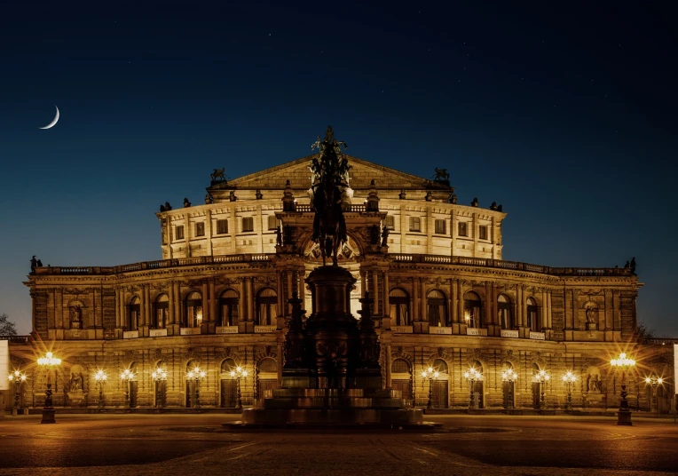 a large building lit up at night with the moon in the sky, a statue, by Alexander Bogen, pexels contest winner, neoclassicism, photo of a huge theaterstage, german renaissance architecture, a large, panzer