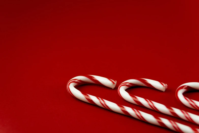 a couple of candy canes sitting on top of a red surface, by Richard Carline, b - roll, clean photo, rhythmic, cr3