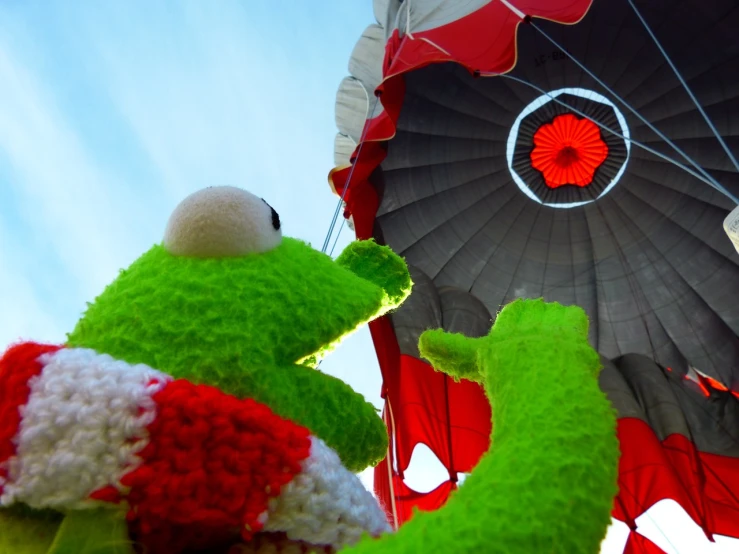 a close up of a stuffed animal near a hot air balloon, precisionism, kermit the frog, round about to start, poppy, version 3