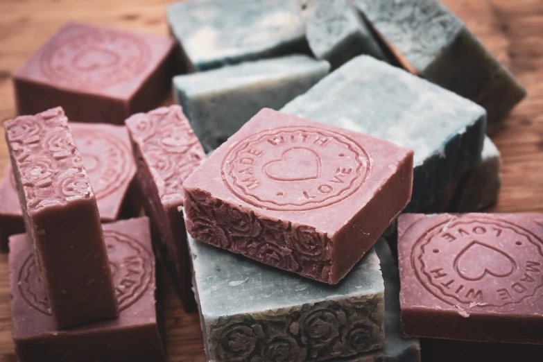 a pile of soap sitting on top of a wooden table, baroque, rose tones, close-up product photo, mauve and cinnabar and cyan, high quality product photo