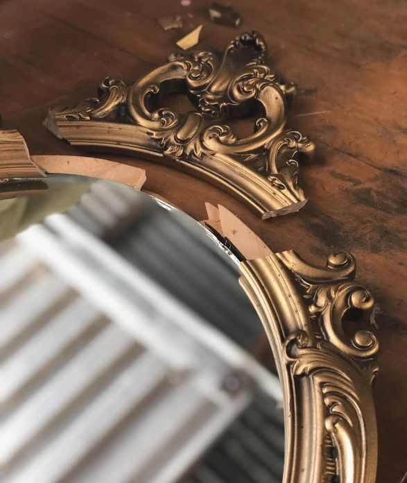 a mirror sitting on top of a wooden table, by Matt Cavotta, baroque, detail shots, gold paint, old home decor, display item