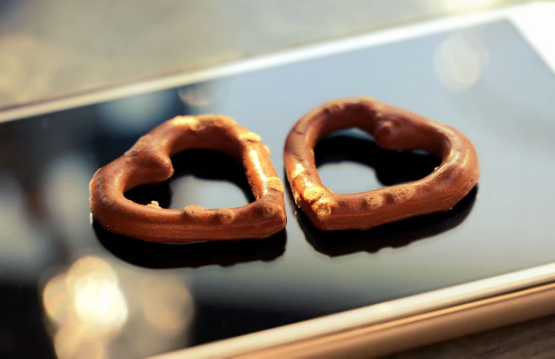 a pair of pretzels sitting on top of a smart phone, romanticism, heart of the internet, istockphoto, bronze, closeup photo