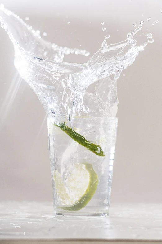 a glass of water with a slice of lime in it, by Jan Rustem, pexels, photorealism, splashing, draped with water and spines, banner, action shot