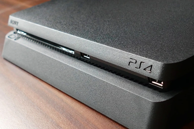 a video game console sitting on top of a wooden table, a picture, ps 4 screenshot, front closeup, grey metal body, detail shot