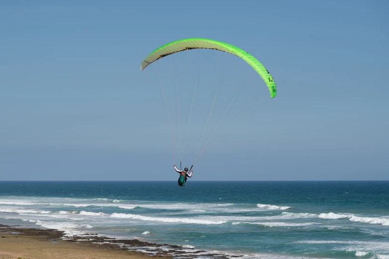 a person parasailing over the ocean on a sunny day, a picture, by Peter Churcher, shutterstock, south african coast, pale green backlit glow, on dune, with two pairs of wings