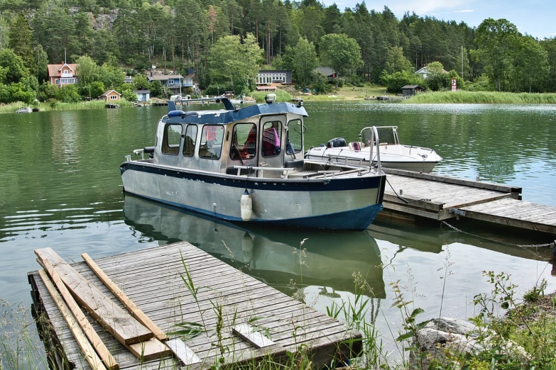 a boat sitting on top of a lake next to a dock, by Jens Jørgen Thorsen, flickr, hurufiyya, anato finnstark. front view, bucklebury ferry, sideview, # 2 2 3 3 e 6