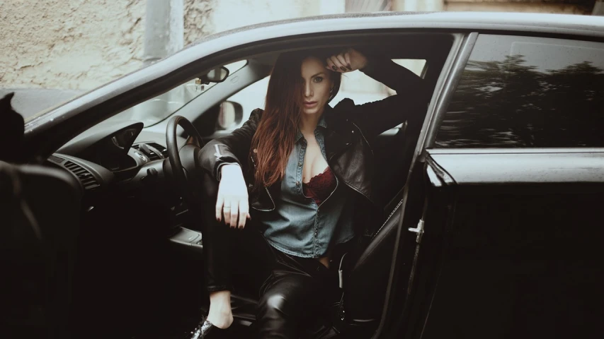 a woman sitting in the passenger seat of a car, inspired by Elsa Bleda, tumblr, renaissance, black leather shiny jeans, beautiful redhead woman, cinematic outfit photo
