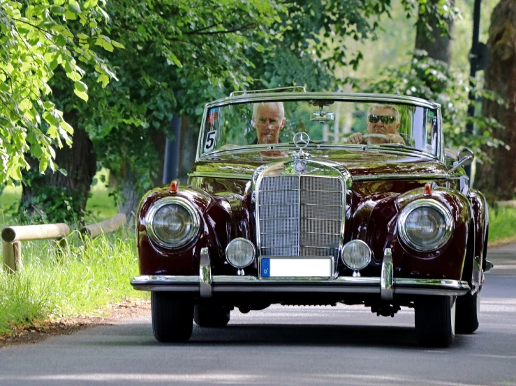 a brown car driving down a road next to a forest, a portrait, by Hans Fischer, pixabay contest winner, baroque, couple, mercedes, featuring rhodium wires, well preserved