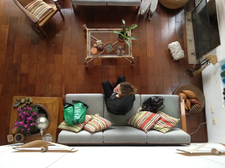 a person laying on a couch in a living room, process art, birds eye view, meredith schomburg, hardwood floors, open plan