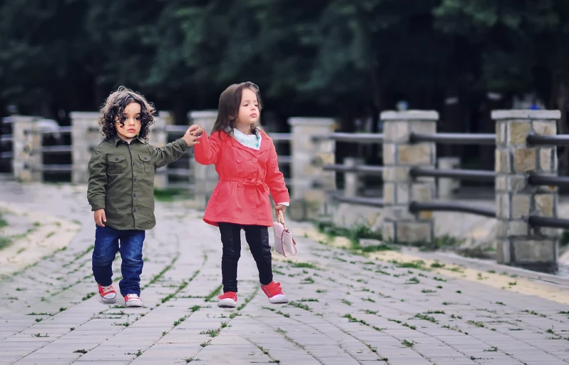 a couple of little girls standing next to each other, by Lilia Alvarado, pexels, incoherents, wearing red jacket, yanjun chengt, couple walking hand in hand, cute boys