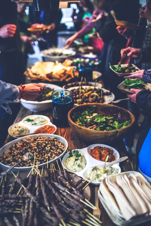 a group of people standing around a table full of food, a picture, by Juan O'Gorman, pexels, reading for a party, 🦩🪐🐞👩🏻🦳, clean image, overflowing feast buffet table