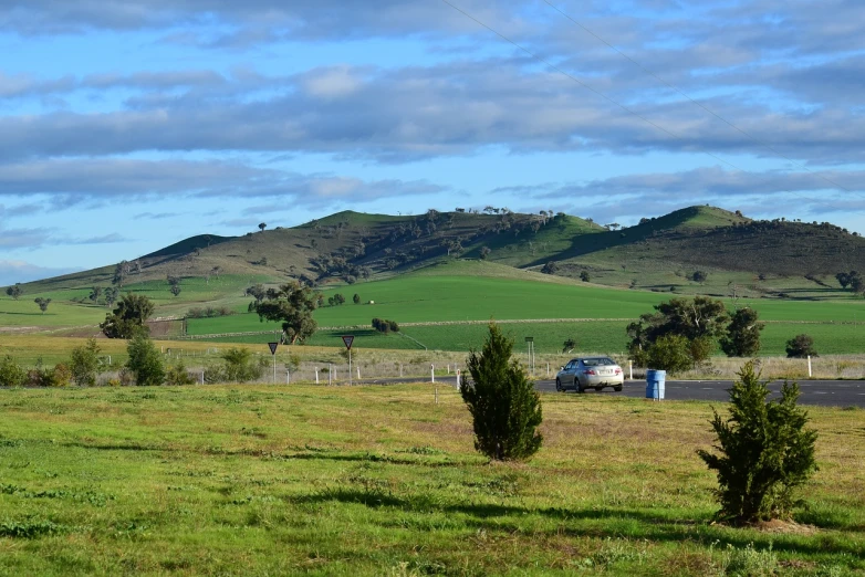 a truck that is sitting in the grass, a picture, by David Simpson, flickr, cypresses and hills, aussie, wide view of a farm, view of villages