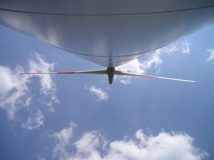 a large jetliner flying through a blue sky, by Jan Rustem, flickr, precisionism, very long shot of a windmill, wideangle pov closeup, on the bow, [ [ hyperrealistic ] ]