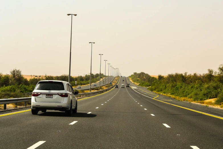 a white car driving down the middle of a highway, a picture, hurufiyya, tanned ameera al taweel, usa-sep 20, infrastructure, 7 7 7 7