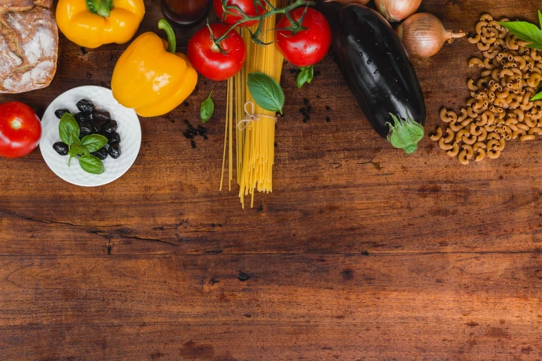 a wooden table topped with lots of different types of food, a still life, pexels, spaghetti, basil leaves instead of leaves, background image, document photo