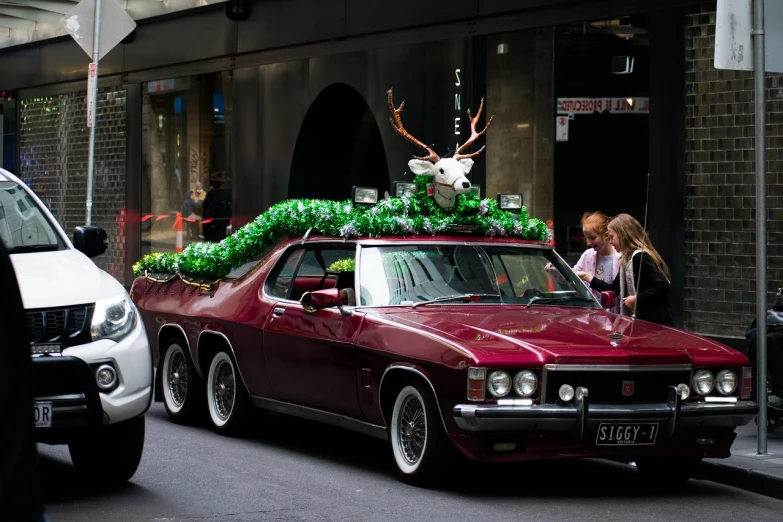 a red car with a deer head on top of it, by Lee Loughridge, flickr, maximalism, sydney, parade, green, subtle giger