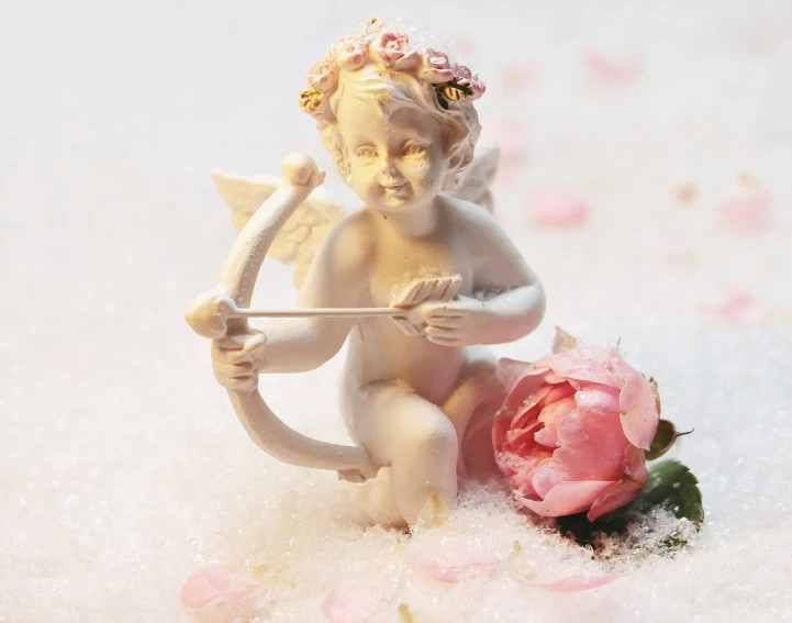 a figurine of a cupid with a bow and a flower, romanticism, pale as the first snow of winter, product introduction photo