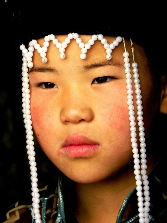 a close up of a child wearing a hat, flickr, mingei, beautiful young female shaman, strings of pearls, a young woman as genghis khan, award winning color photo