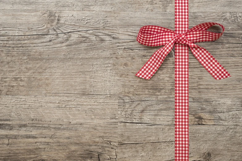 a red and white checkered bow on a wooden table, minimalism, abcdefghijklmnopqrstuvwxyz, gifts, wood effect, uncropped