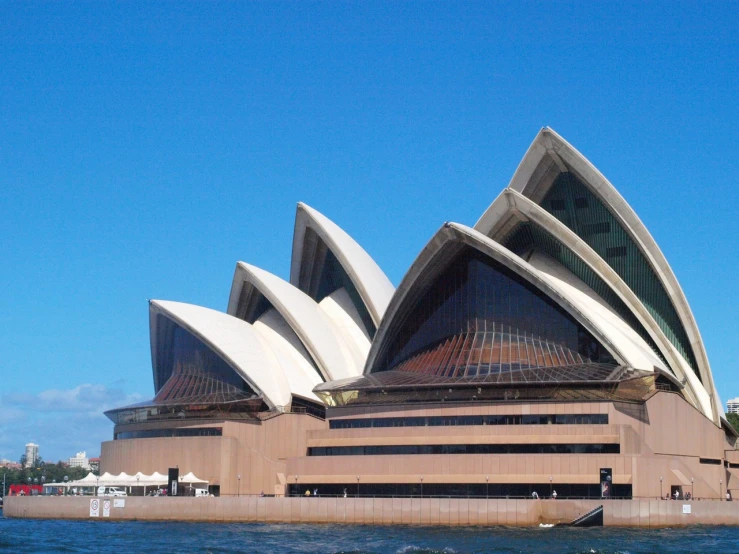 a large building sitting on top of a body of water, inspired by Sydney Carline, very attractive, buttresses, screens, blue sky