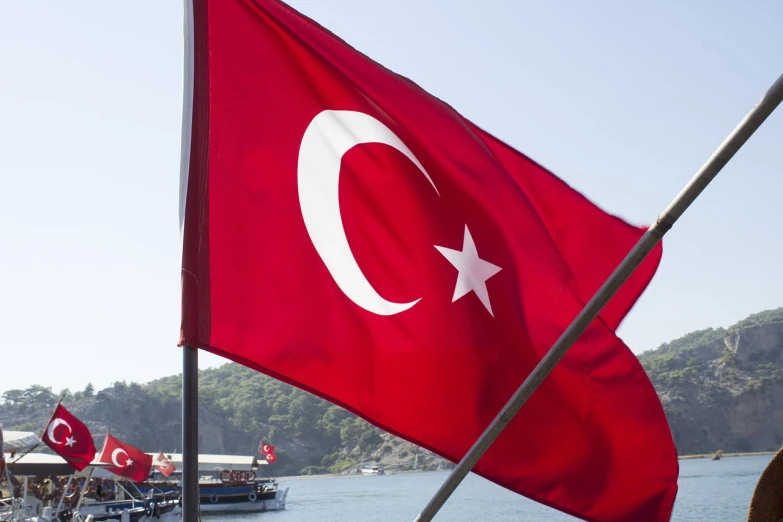 a turkish flag flying over a body of water, pexels, hurufiyya, istockphoto, harbor, close up shot from the side, tourist photo