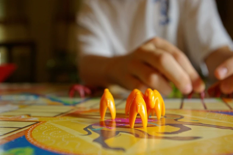 a close up of a person playing a board game, by Jessie Algie, grasping pseudopods, yellow and orange color scheme, camels, macro image