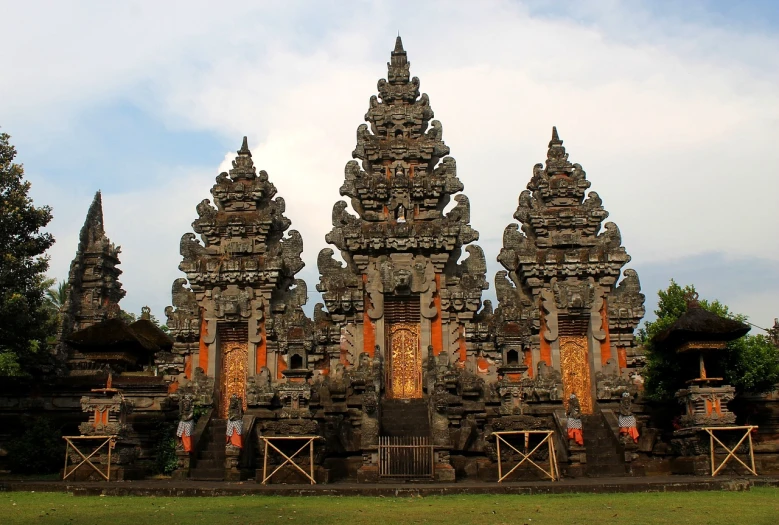 a group of statues sitting on top of a lush green field, a picture, sumatraism, symmetrical complex fine detail, three towers, elaborate carved wood balconies, wonderful masterpiece