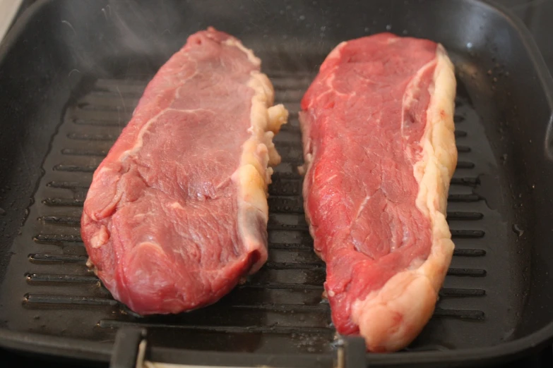 two pieces of meat are cooking in a frying pan, a picture, sideburns, grills, pale-skinned, meat veins