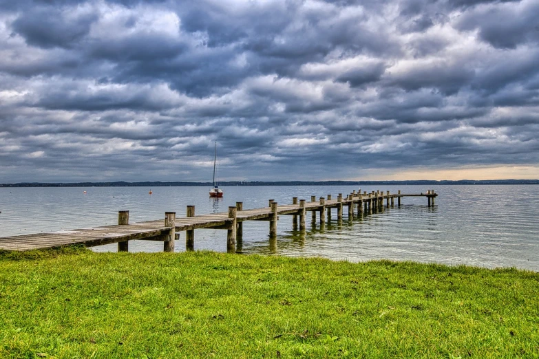 a pier next to a body of water under a cloudy sky, a stock photo, by Hans Schwarz, pixabay, visual art, bucklebury ferry, sailboat, hdr photo, high res photo