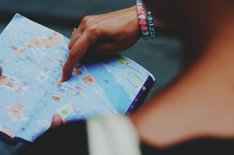 a close up of a person holding a map, by Matija Jama, pexels, happening, 🕹️ 😎 🔫 🤖 🚬, diary on her hand, oh the places you'll go, screengrab