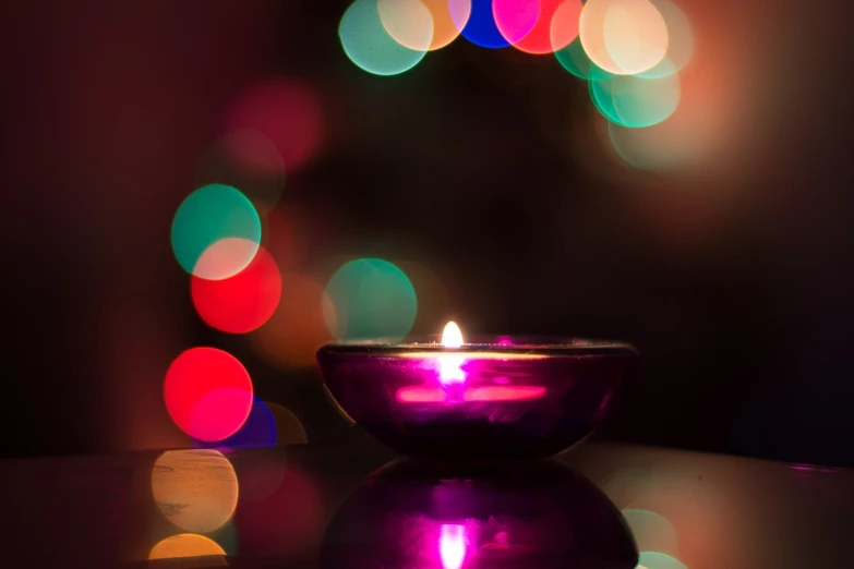 a lit candle sitting on top of a table, a picture, by January Suchodolski, pexels, light and space, rim lights purple and green, bokeh. brian spilner, purple and red, holy aura