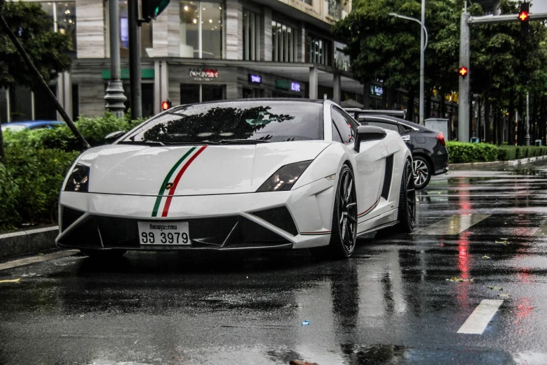 a white sports car driving down a wet street, a photo, by Elias Ravanetti, tumblr, bangkok, lamborghini, trimmed with a white stripe, boston