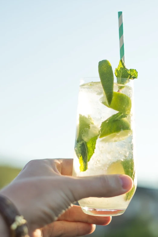 a close up of a person holding a drink, by Mathias Kollros, shutterstock, light greens and whites, sparkling in the sunlight, rum, professional work