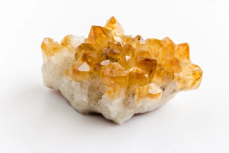 a cluster of yellow crystals on a white surface, by Kristin Nelson, amethyst, high detail product photo