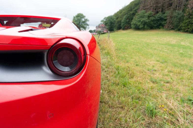 a red sports car parked in a field, shutterstock, pov from rear, ferrari 458, frontlight, dezeen