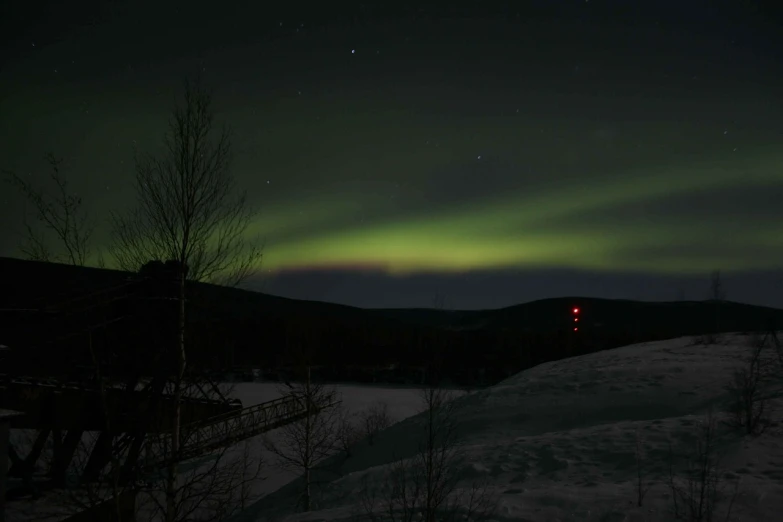 a couple of people standing on top of a snow covered slope, by Jakob Häne, flickr, hurufiyya, very dark with green lights, 1 glowing bridge crossing river, solar storm, minna sundberg