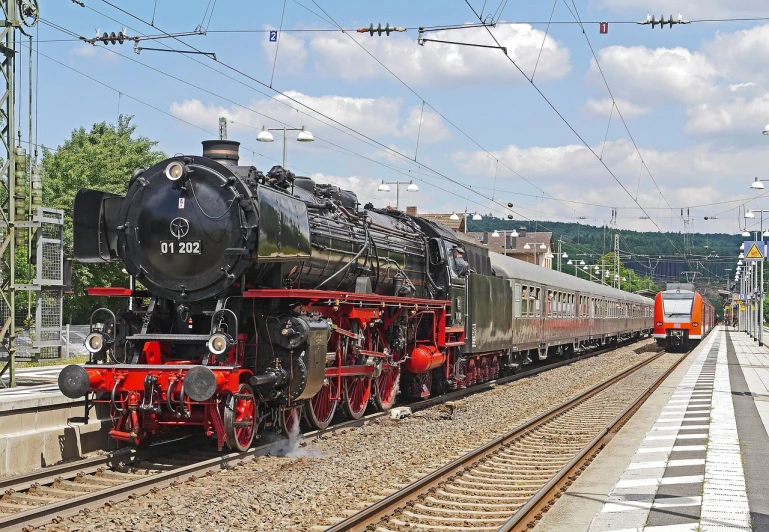 a train traveling down train tracks next to a train station, by Jörg Immendorff, pixabay, brass and steam technology, summer day, posing for camera, profile picture 1024px