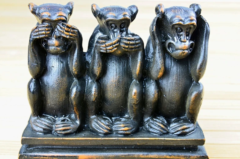a statue of three monkeys sitting on top of a wooden table, trending on pixabay, panels, speak no evil, glimmering, 🦩🪐🐞👩🏻🦳