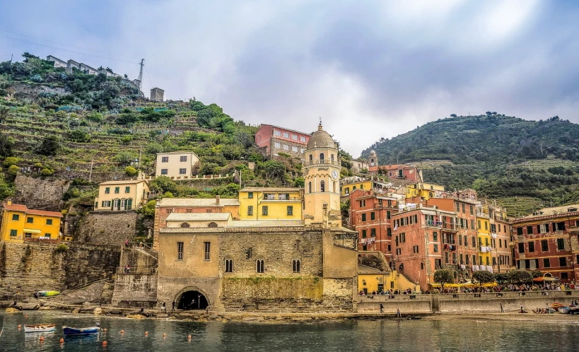 a group of buildings sitting on top of a hill next to a body of water, by Carlo Martini, pexels, renaissance, vibrant but dreary gold, cinq terre, faded red and yelow, stock photo