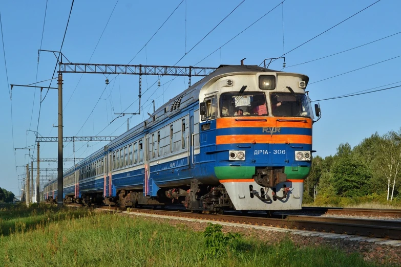 a blue and orange train traveling down train tracks, by Maksimilijan Vanka, flickr, hurufiyya, rostov city, summer morning, front profile, scp 3008