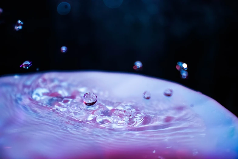 a close up of a frisbee with water droplets, a macro photograph, by Jan Rustem, pexels, digital art, purple and blue colored, pink water in a large bath, swarovski crystals, glowing threads of drop