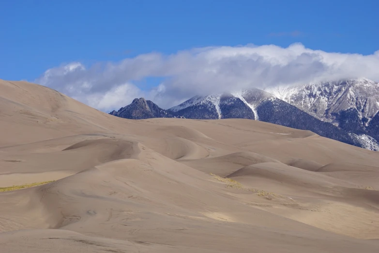 a person riding a horse in the desert, a photo, flickr, snowy peaks, victorian arcs of sand, sandman, wide shot photo