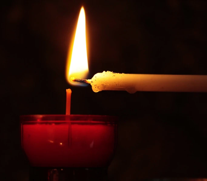 a lit candle sitting on top of a red cup, pexels, candlelit catacombs, istockphoto, pouring, close photo