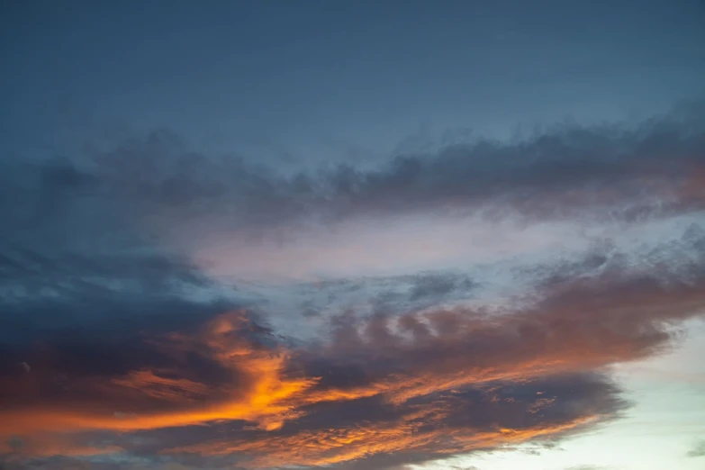 a couple of people standing on top of a beach under a cloudy sky, a picture, romanticism, vibrant sunset dramatic sky, orange and blue colors, layered stratocumulus clouds, night clouds