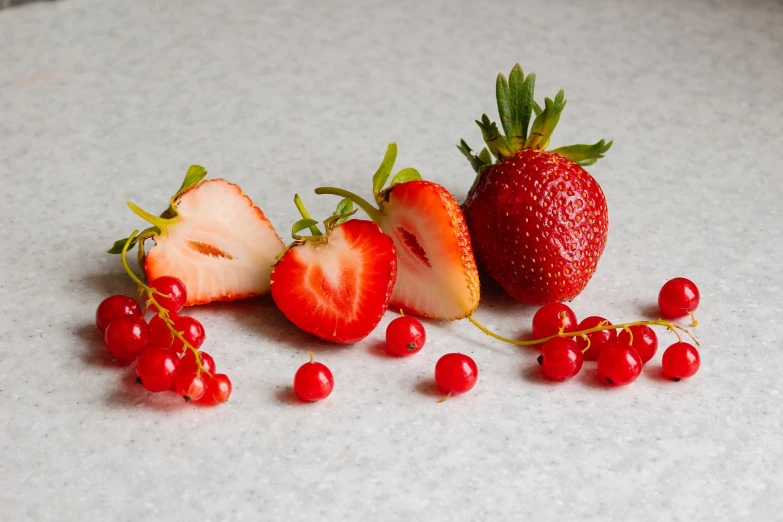 a close up of strawberries and a strawberry on a table, a still life, voge photo