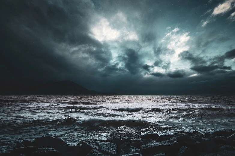 a large body of water under a cloudy sky, a picture, shutterstock, romanticism, dark stormy night, chaotic sea setting, shore, eerie mood