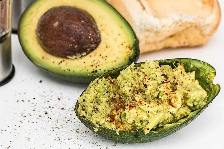 a close up of an avocado cut in half, by Judith Gutierrez, pexels, brown bread with sliced salo, humus, with a white background, background image